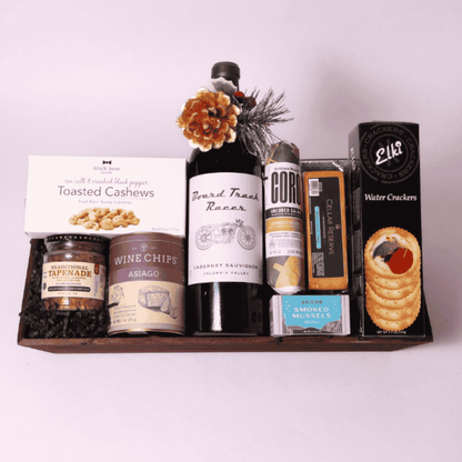 High-end corporate gift basket with unique items: Florentina sparkling spritz, smoked mussels, cashews, tapenade, and artisan crackers, perfect for holiday gifting.