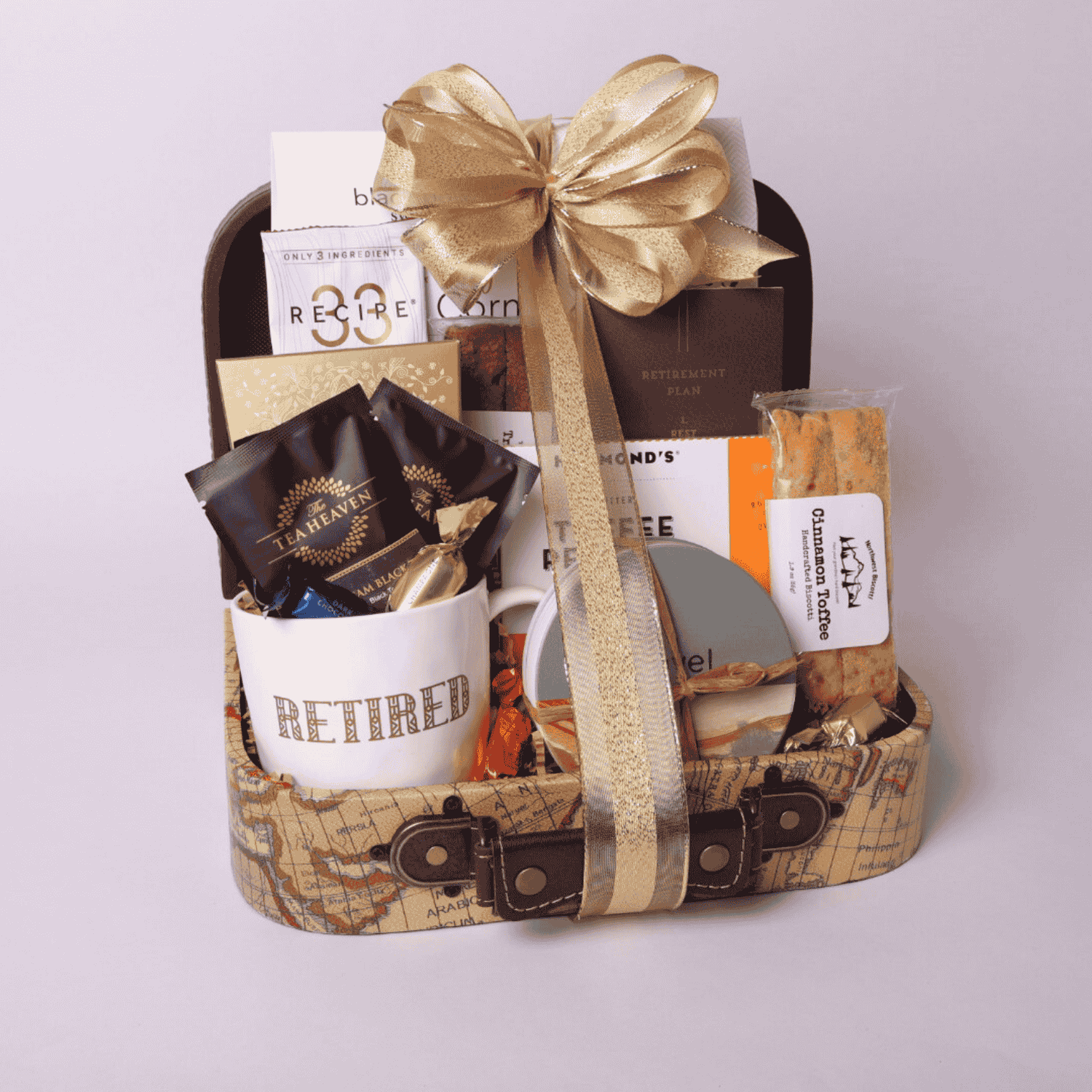 Retirement gift basket with travel themed goodies.  Basket includes travel snacks, retirement mug, stone coasters, and notebook all assembled in a decorative mini suitecase.