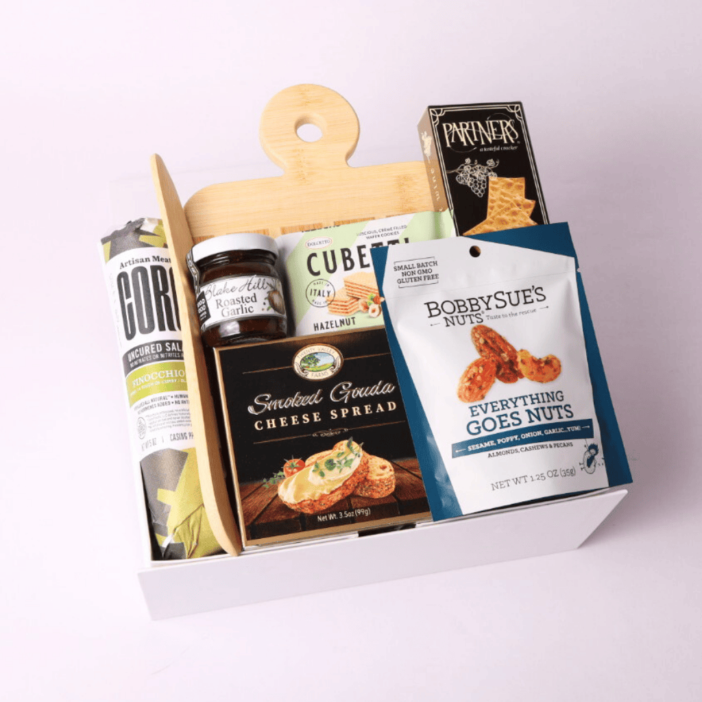 Simply Savory Gift Box featuring a bamboo paddle board, spreading knife, gourmet crackers, salami made in WA, cheese spread, savory jam, nuts, and hazelnut wafer cookies, perfect for hostess or housewarming gifts.