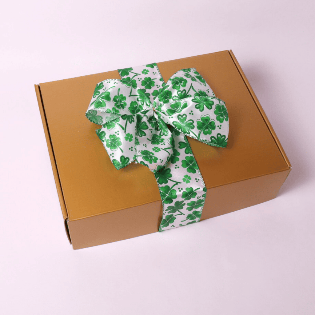 A luxurious gold gift box with a festive green shamrock ribbon, packed with Irish-themed goodies for the perfect St. Patrick’s Day celebration.